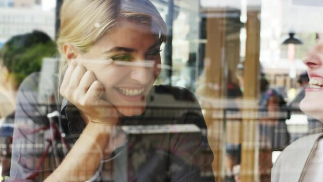 Window of cafe, women and friends with chat or laughing together for brunch or lunch, catch up or reunion. Communication, happiness and meeting at coffee shop for social gathering and funny story