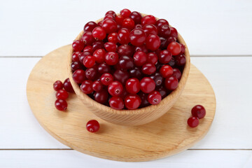 Fresh ripe cranberries in bowl on white wooden table, closeup
