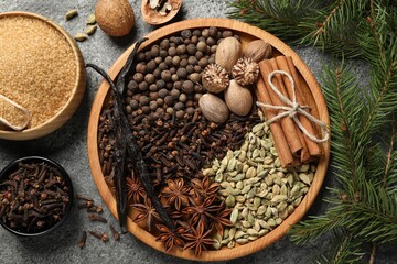 Different spices, nuts and fir branches on gray textured table, flat lay