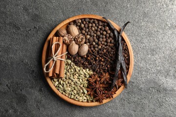 Different spices and nuts on gray textured table, top view