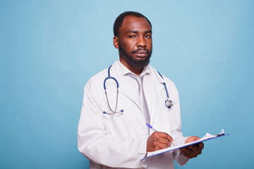 African american medic practitioner grasping a clipboard while gazing at the camera. Black male...