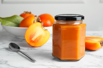 Delicious persimmon jam and fresh fruits on white marble table