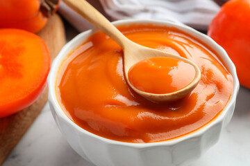 Delicious persimmon jam and fresh fruits on table, closeup