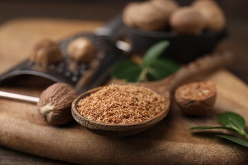 Spoon with grated nutmeg on wooden board, closeup
