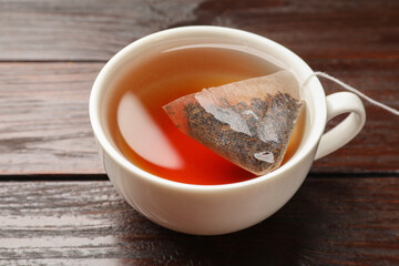 Tea bag in cup on wooden table, closeup