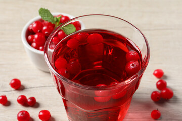 Tasty refreshing cranberry juice and fresh berries on light wooden table, closeup