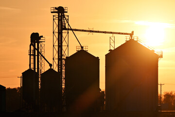Silhouetted Grain Bins at Sunset - Powered by Adobe