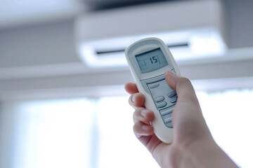 Close up image of hand holding an air conditioning remote control and adjusting the temperature