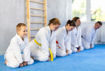 Fototapeta na wymiar Family in gym at group karate training with trainer are in sitting position