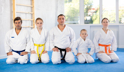 Parents with children boy and teen girl students of Academy of martial Arts together with male teacher in gym. Advertising banner for school of martial arts, teaching physical education lessons