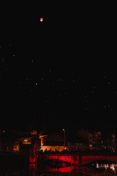 Nighttime sky lantern festival over illuminated bridge