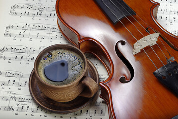 beautiful antique violin on a background of notes and cup of coffee