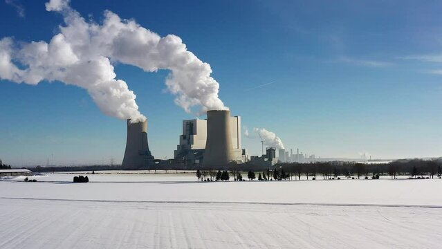 Approach with a drone to a German coal-fired power plant in a snow-covered landscape in the Rhineland, North Rhine-Westphalia, Germany