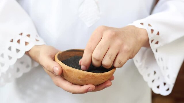Priest holding a bowl of ashes during Ash Wednesday celebration. 