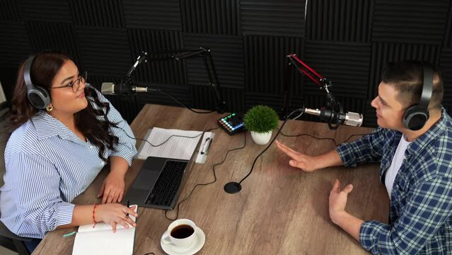 Top view of a radio host and guest talking during an interview for a talk show in a recording studio