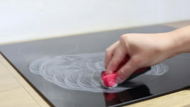 woman washes electric stove with paste