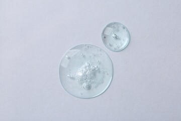 Drops of cosmetic serum on white background, top view