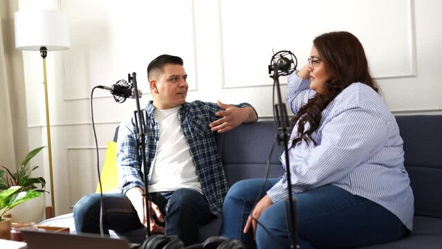 Talk show host and guest recording an interview while relaxing and sitting in a living room