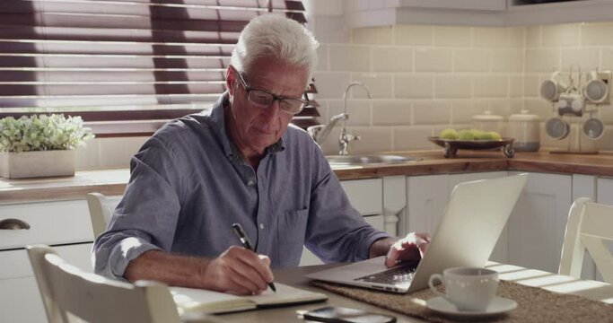 Home laptop, journal and old man writing business info, schedule or summary of feedback report, data or plan. Kitchen, notebook and mature person doing research, remote work and work on project notes