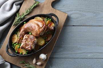 Tasty cooked rabbit with vegetables in baking dish on grey wooden table, top view. Space for text