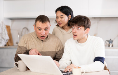 Friendly family watches something together on the Internet or video chats via a laptop