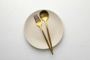 Clean plate, fork and spoon on white table, top view