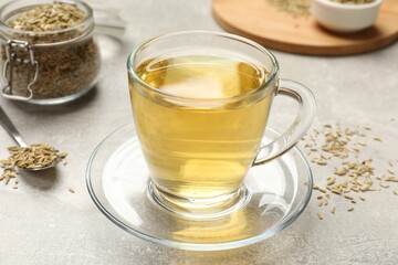 Aromatic fennel tea and seeds on light grey table, closeup