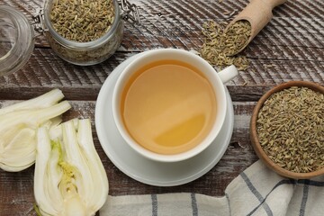 Aromatic fennel tea, seeds and fresh vegetable on wooden table, flat lay