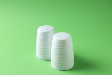 Salt and pepper shakers on green background