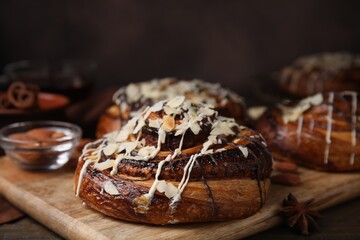 Delicious rolls with toppings and nuts on wooden table, closeup. Sweet buns