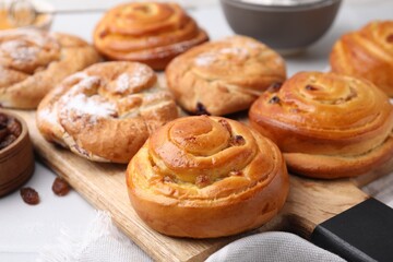 Obraz na płótnie Canvas Delicious rolls with raisins and powdered sugar on table, closeup. Sweet buns