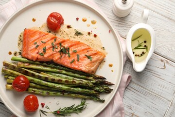 Tasty grilled salmon with tomatoes, asparagus and spices on table, flat lay
