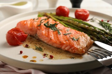 Tasty grilled salmon with tomatoes, asparagus and spices served on table, closeup