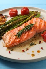 Tasty grilled salmon with tomatoes, asparagus and spices on table, closeup