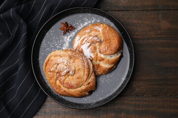 Delicious rolls with sugar powder and anise star on wooden table, top view. Sweet buns