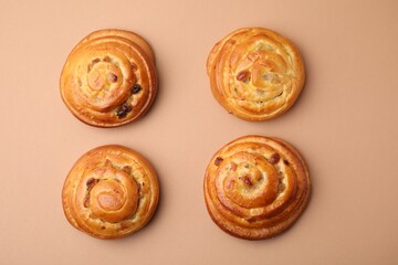 Delicious rolls with raisins on beige table, flat lay. Sweet buns