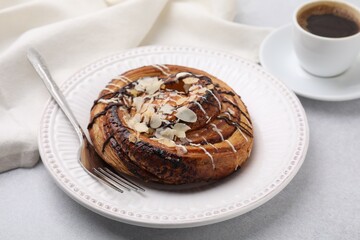 Delicious roll with poppy seeds, topping and fork served on light table, closeup. Sweet bun