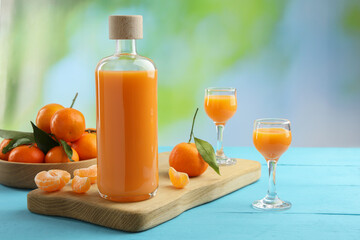 Delicious tangerine liqueur and fresh fruits on light blue wooden table