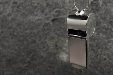 Referee equipment. Metal whistle on grey textured background, closeup and space for text