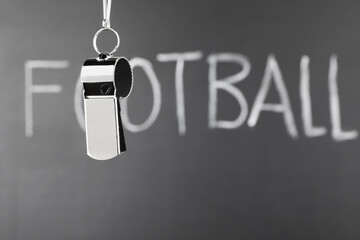 Referee whistle against chalkboard with word Football, closeup. Space for text