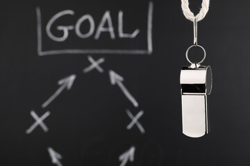Referee whistle against chalkboard with game scheme, closeup. Space for text