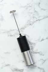 Black milk frother wand on white marble table, top view