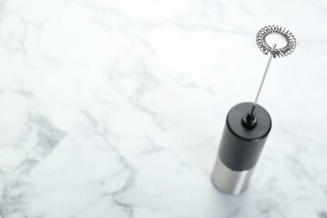 Black milk frother wand on white marble table. Space for text