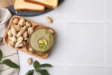 Tasty pistachio cream and nuts served on white tiled table, flat lay. Space for text - obrazy, fototapety, plakaty