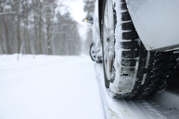 Car with winter tires on snowy road outdoors, closeup. Space for text