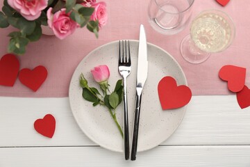 Romantic place setting with flowers and red paper hearts on white wooden table, flat lay. St. Valentine's day dinner