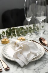 Beautiful place setting with candles and eucalyptus on white marble table