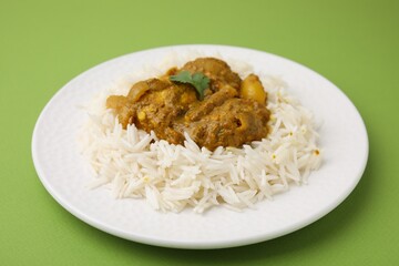 Delicious chicken curry with rice on green background, closeup