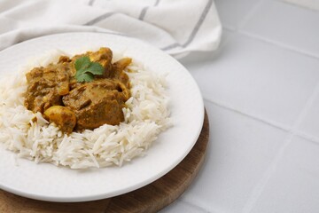 Delicious chicken curry with rice on white tiled table, closeup