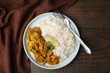 Delicious chicken curry with rice on wooden table, top view